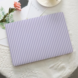 May include: A rectangular laptop skin with a vertical striped pattern in light purple and white. The word "RENG" is partially visible on a white card. A pink rose and green leaves are in the upper left corner.
