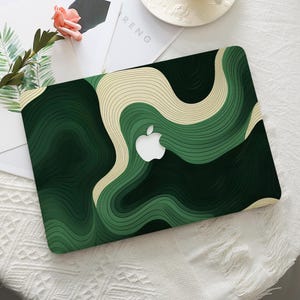 May include: Green and cream abstract swirl pattern laptop skin with a white apple logo in the centre.