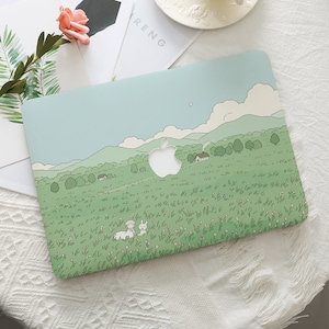 May include: A light green laptop case with a countryside design, showing green hills, trees, and houses under a light blue sky. The Apple logo is cut out. A cartoon rabbit and person are in the foreground.