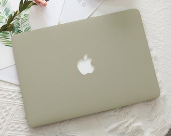 以下が含まれることがあります： Appleのロゴが付いた、明るい緑色のAppleノートパソコン。ノートパソコンは、背景に花と緑のある白い表面に置かれています。「RENG」という単語が部分的に表示されています。