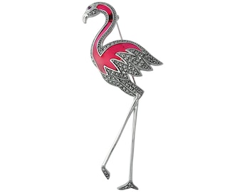 May include: A flamingo brooch with a silver-tone metal body and legs. The flamingo's body is a vibrant pink with a black marcasite design on the wings. The bird has a small red gem for an eye.