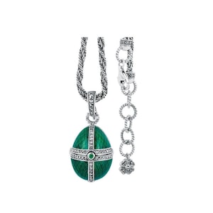 May include: A silver necklace featuring a green enamel egg pendant. The egg is adorned with a cross and small gemstones. The chain is crafted from twisted silver links.