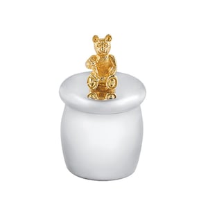 Puede incluir: Una caja de recuerdo de plata con una figurita de oso de oro en la tapa. La caja es redonda y tiene un acabado liso y pulido.