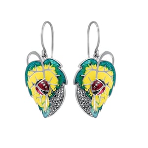 May include: Silver earrings featuring a yellow and green leaf design with a red ladybug on each leaf. The leaves are adorned with small, sparkling stones.