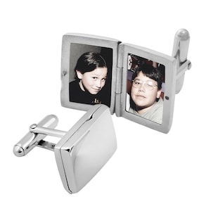 Könnte beinhalten: Silberne Manschettenknöpfe mit einem Klapprahmen, der sich öffnet und zwei Schwarzweißfotos von jungen Menschen zeigt. Die Manschettenknöpfe haben eine rechteckige Form.