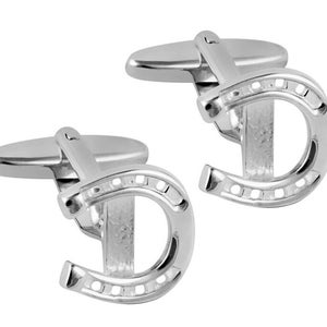 Puede incluir: Un par de gemelos de plata en forma de herradura. Los gemelos están hechos de metal y tienen un acabado brillante.