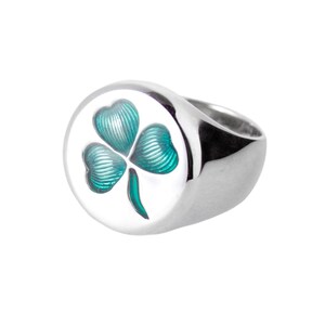 Op de afbeelding: Een zilveren ring met een rond, verhoogd ontwerp met een groen klavertje vier.