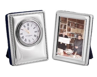 Könnte beinhalten: Ein verziertes Set aus einer silberplattierten Uhr und einem Bilderrahmen mit Perlenrand. Das Zifferblatt der Uhr hat römische Ziffern und den Text 'Art. D. Norman, London'. Der Bilderrahmen zeigt ein Schwarzweißfoto von zwei Männern in einer Bibliothek.