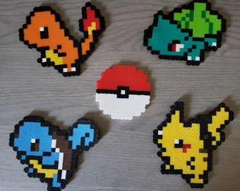 May include: Five pixel art Pokemon characters made with colorful beads. The characters are Charmander, Bulbasaur, Squirtle, Pikachu, and a Pokeball.