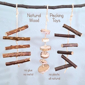 Könnte beinhalten: Natürliche Holz- und Birkenholzspielzeuge, die an einem Ast hängen. Die Holzspielzeuge sind mit Schnur aneinandergereiht. Der Text "Naturholz" und "Pickspielzeug" ist auf dem Bild zu sehen. Der Text "kein Kleber, kein Metall, kein Plastik, alles natürlich" ist ebenfalls auf dem Bild zu sehen.