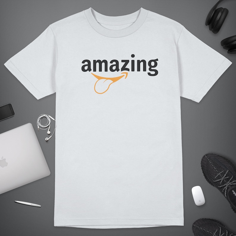 Peut inclure: T-shirt blanc avec le mot "amazing" imprim&eacute; en noir avec un sourire stylis&eacute; Amazon orange.
