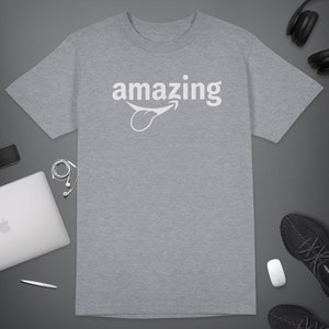 Peut inclure: Un t-shirt gris chin&eacute; avec le mot "amazing" imprim&eacute; en blanc avec une langue de dessin anim&eacute; qui sort.