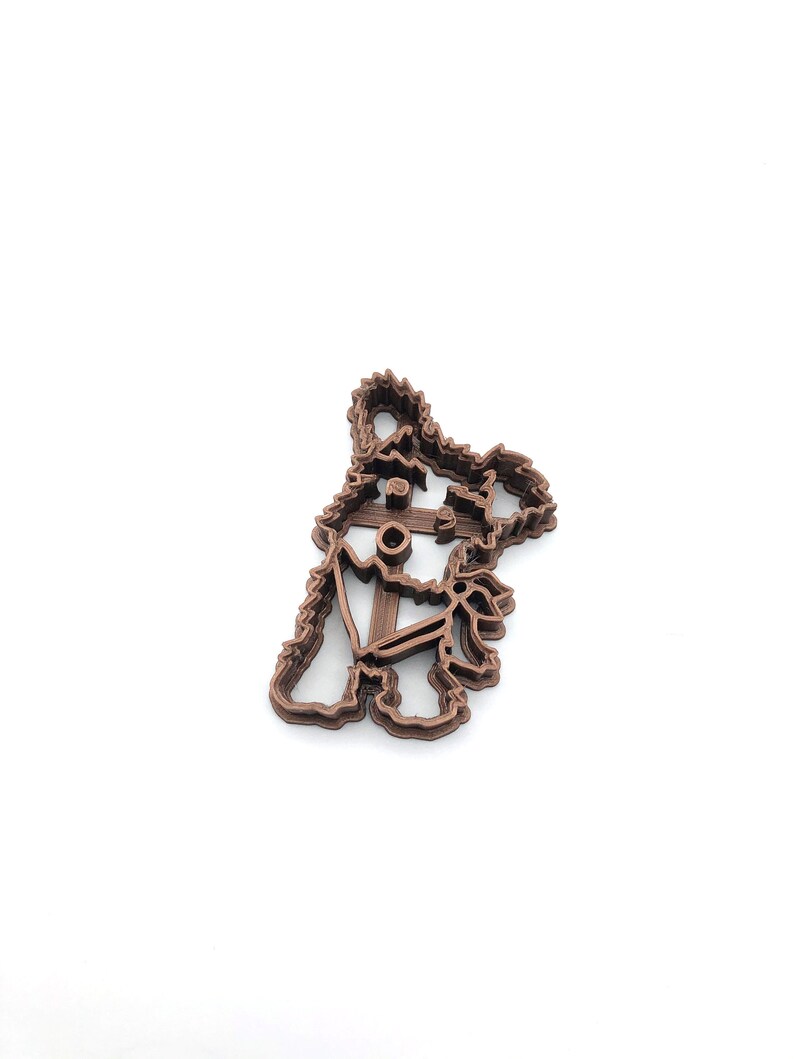 May include: A brown 3D printed cookie cutter shaped like a dog with an anchor on its chest.