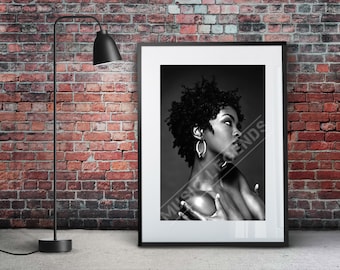 May include: Black and white photograph of a woman with curly hair wearing large hoop earrings. The woman is looking to the right and has her hands clasped in front of her.