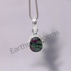 May include: A silver pendant featuring a green and pink oval gemstone. The pendant is suspended from a silver chain.
