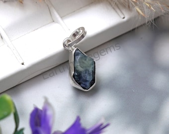 May include: A silver pendant featuring a raw blue kyanite gemstone. The pendant is shaped like a rough crystal and has a silver bail for attaching to a chain.