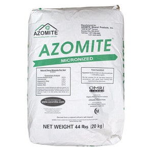 May include: A white bag of AZOMITE micronized natural trace minerals for soil. The bag has green and black text, including the net weight of 44 lbs. The product is derived from a natural volcanic ash deposit.