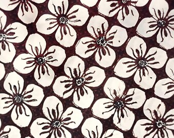 Könnte beinhalten: Nahaufnahme eines weißen Stoffes mit einem sich wiederholenden Muster aus braunen Blüten. Die Blüten haben fünf Blütenblätter und eine dunkle Mitte.
