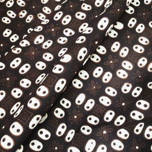 May include: A close-up of a brown fabric with a white pattern of small circles and squares. The fabric has a subtle sheen and a soft texture.