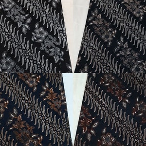Op de afbeelding: Een stof met een zwarte achtergrond en een herhalend batikpatroon van witte en bruine bloemmotieven en verticale golvende lijnen. Het ontwerp toont ingewikkelde botanische details en vloeiende, ritmische vormen over het textieloppervlak.