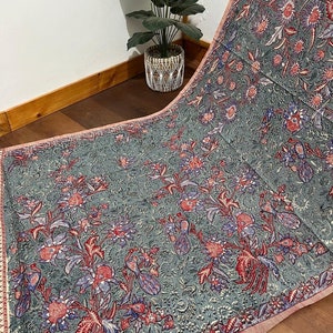 Peut inclure: Un tissu gris avec un motif floral dans les tons de rouge, bleu et blanc. Le tissu a une bordure rose.