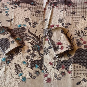 May include: A beige fabric with a brown and blue batik pattern. The fabric is folded into two squares and features a floral design.