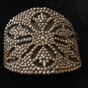 May include: A silver-toned metal bracelet with a decorative design of small, raised circles and a starburst pattern.