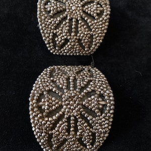 May include: Two silver-toned metal embellishments with a circular design of raised dots and a starburst pattern.