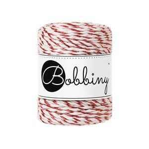 May include: A spool of red and white twine with a metallic sheen. The label on the spool reads "Bobbiny" in a cursive font, set against a black oval. The twine is tightly wound, showcasing a decorative, festive appearance.