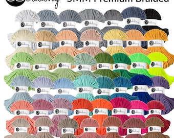 May include: A collection of Bobbiny 5MM Premium Braided yarn in various colors. The yarn is arranged in neat bundles, showcasing a wide spectrum of hues, including white, gray, green, blue, orange, pink, and brown. The Bobbiny logo is visible on each label.