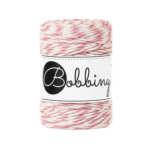 May include: A spool of pink and white striped twine with the word "Bobbiny" printed on the label.