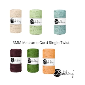 May include: An assortment of 3MM Macrame Cord Single Twist in various colors, including cream, green, and teal. The image also features cords in burgundy, olive green, and peach. Each spool has a label with the brand name "Bobbing".