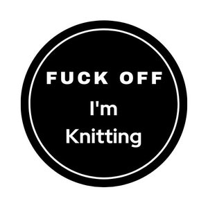 以下が含まれることがあります： 白い縁と白いテキストで「FUCK OFF I'm Knitting」と書かれた黒い円形のグラフィックデザイン。 このデザインはシンプルで大胆で、編み物に最適です。