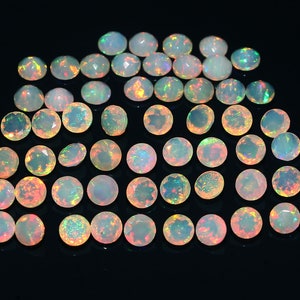 May include: A collection of 40 round, iridescent opal gemstones. The opals are various shades of white, with flashes of rainbow colors.