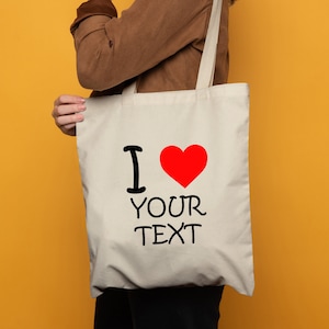 May include: A white canvas tote bag with a red heart and the text "I love your text".