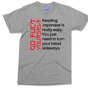 May include: A heather grey t-shirt with a humorous message about reading Japanese. The text reads: "GO チムCケソロムヤラモレチ Reading Japanese is really easy. You just need to turn your head sideways."