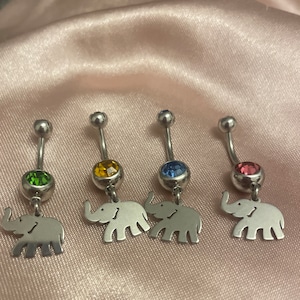May include: Four silver belly button rings with elephant charms. Each ring has a different colored gem: green, yellow, blue, and pink.