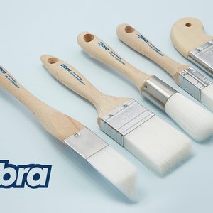 May include: A set of five paint brushes with wooden handles and white bristles. The brushes are labelled "Zebra" and are arranged in a row on a light blue background.