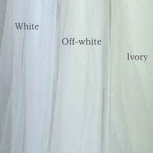 May include: A vertical image showcasing three fabric swatches in varying shades of white: white, off-white, and ivory. The names of the colors are printed on the fabric. The sheer material is likely tulle or a similar lightweight fabric.