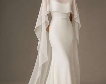 Könnte beinhalten: Ein weißes Brautkleid mit figurbetonter Silhouette und einem transparenten, fließenden Umhang. Das Kleid hat einen U-Boot-Ausschnitt und eine lange Schleppe. Der Umhang fällt über die Schultern und reicht bis zum Boden.