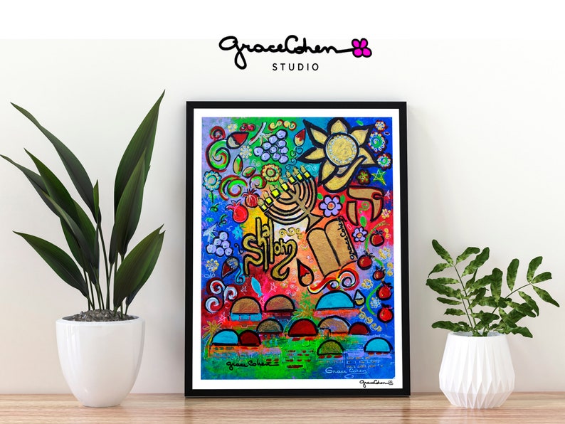 Puede incluir: Impresi&oacute;n art&iacute;stica abstracta y colorida enmarcada en negro. La obra presenta una vibrante mezcla de colores y formas, incluyendo una menor&aacute;, un sol y texto hebreo. La firma del artista es visible. La impresi&oacute;n se exhibe sobre una superficie de madera.