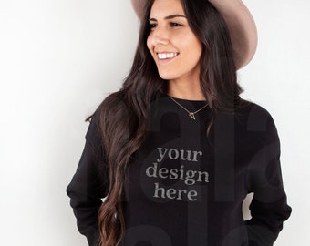 May include: A woman wearing a black cropped sweatshirt with the text "your design here" on the front. She is also wearing a brown fedora and blue jeans.