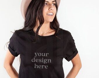 May include: A woman wearing a black t-shirt with the text "your design here" printed on it. She is also wearing a light brown hat and blue jeans.