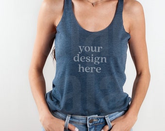 May include: A woman wearing a blue tank top with the text "your design here" printed on the front. She is wearing blue jeans and has her hands in her pockets.
