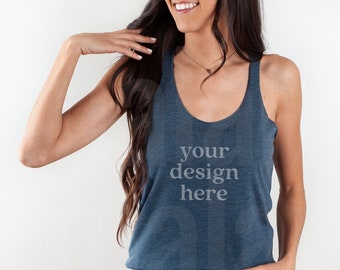 May include: A woman wearing a blue tank top with the text "your design here" printed on the front. She is smiling and looking to the side. She is wearing blue jeans.