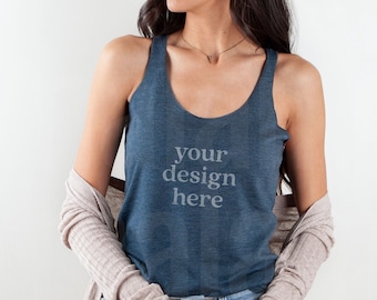 May include: A woman wearing a blue tank top with the text "your design here" printed on the front. She is also wearing a light brown cardigan and blue jeans.