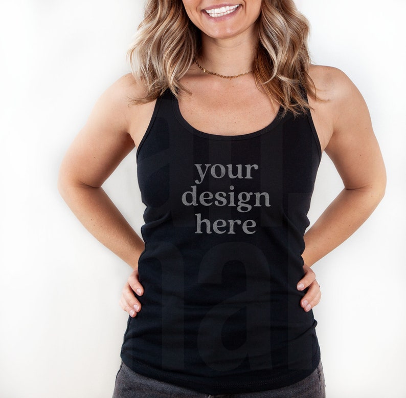 May include: Black tank top with a scoop neck and the text "your design here" in a light grey font. The tank top is a solid color and is worn by a person with their hands on their hips.