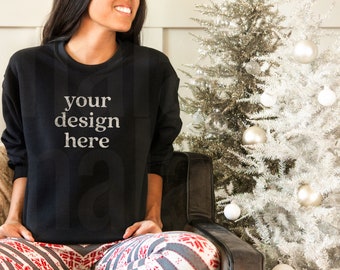 May include: A black sweatshirt with the text "your design here" in white. The person is wearing red and white patterned pajama pants. A silver Christmas tree with white ornaments is in the background.