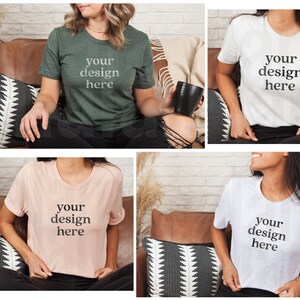 May include: Four different t-shirts with the text "your design here" on them. The shirts are in various colors, including green, white, pink, and gray. The shirts are being modeled by people sitting on couches.