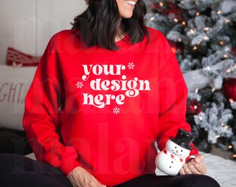 May include: A red sweatshirt with the text "your design here" in white. The sweatshirt is decorated with snowflakes. A person is wearing the sweatshirt and holding a snowman mug.